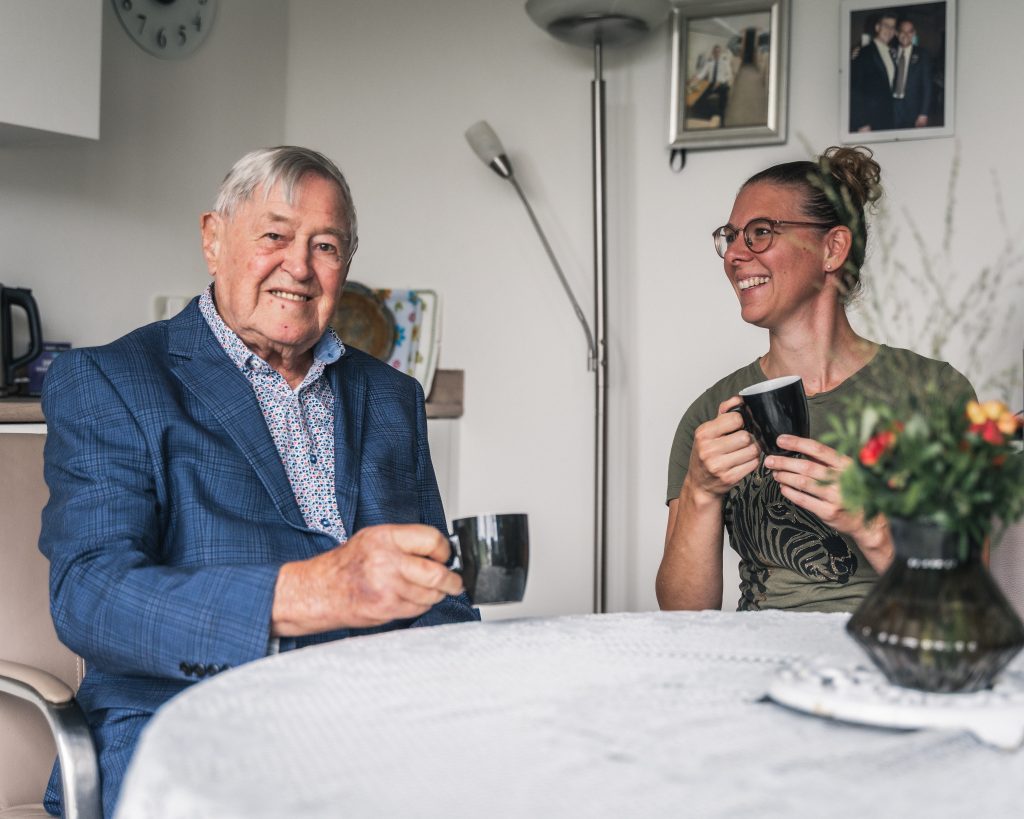 Bewoner en verzorger drinken koffie aan tafel