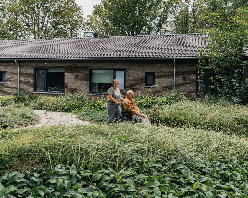 Bewoner en verzorger wandelend door tuin